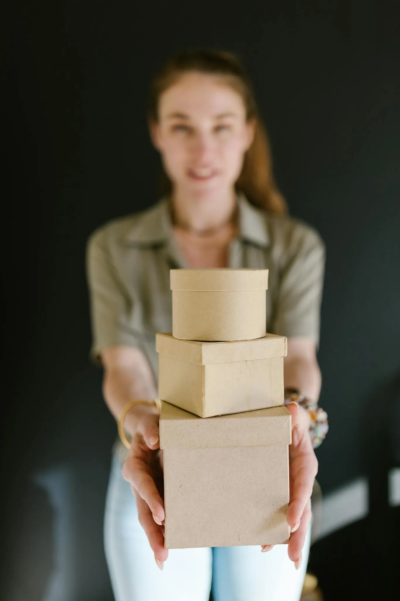 Bee Digital Marketing Agency Blurred woman holding a stack of cardboard boxes, ideal for concepts of e-commerce and small business.